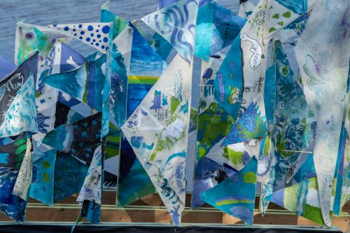 A close up of a collection of blue, green and purple painted triangular shaped flags.